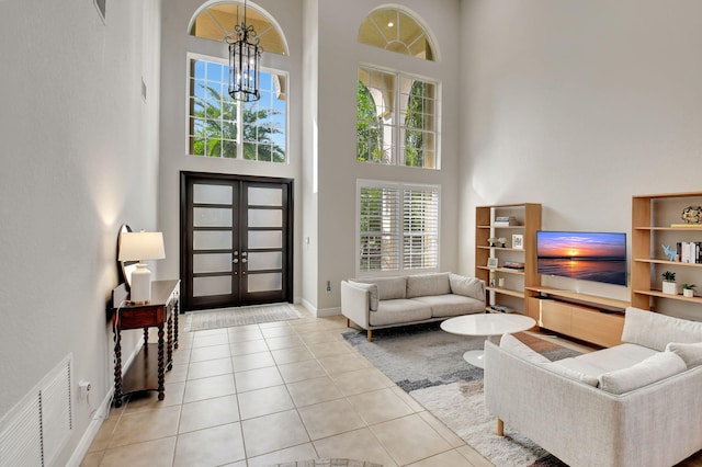 tiled living room with a chandelier, a high ceiling, and french doors