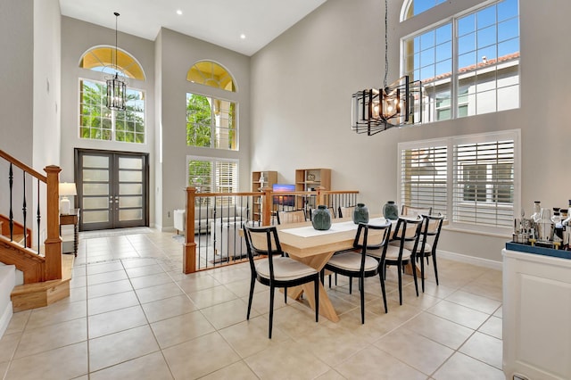 tiled dining area with french doors, a towering ceiling, and a notable chandelier