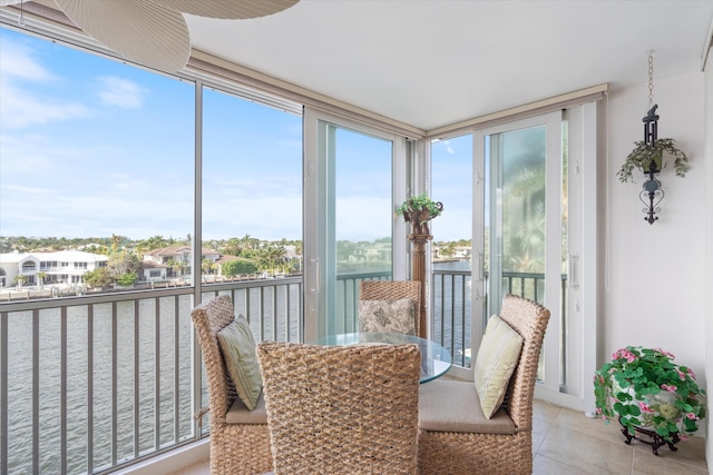 sunroom / solarium featuring expansive windows, a water view, and tile patterned floors