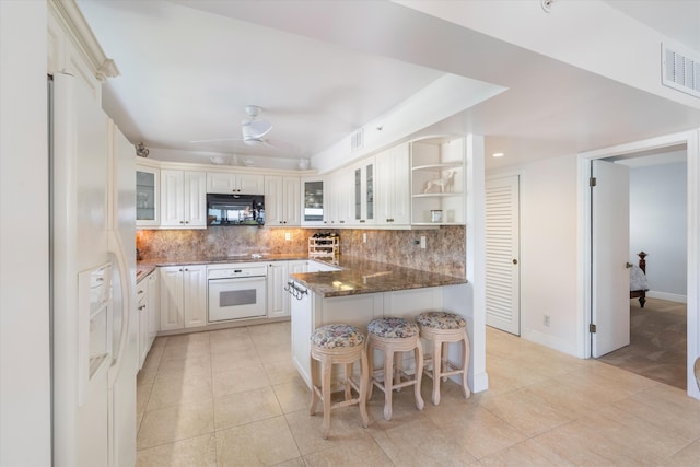 kitchen featuring black appliances, kitchen peninsula, ceiling fan, dark stone countertops, and white cabinetry