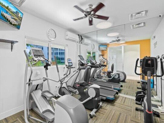 exercise room with an AC wall unit and ceiling fan