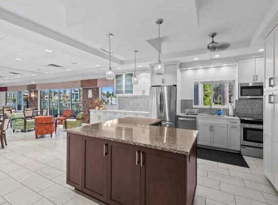 kitchen with ceiling fan, stainless steel appliances, decorative light fixtures, decorative backsplash, and white cabinets