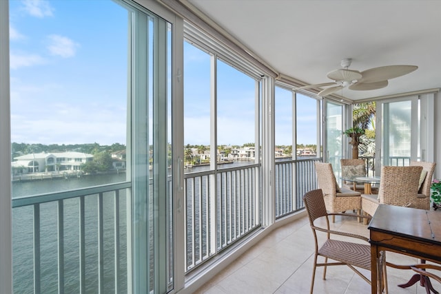 sunroom with plenty of natural light, ceiling fan, and a water view