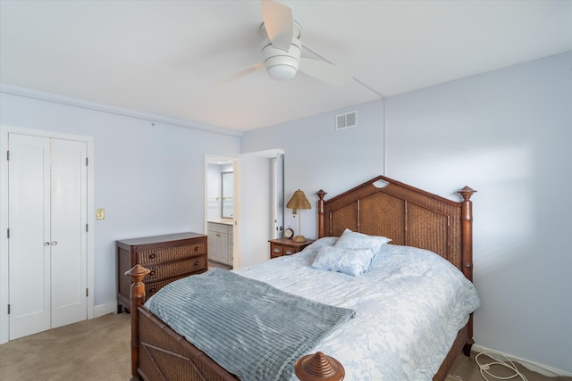 bedroom with ceiling fan, ensuite bathroom, light carpet, and a closet