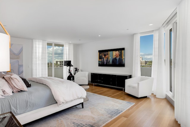 bedroom featuring multiple windows, expansive windows, and light wood-type flooring