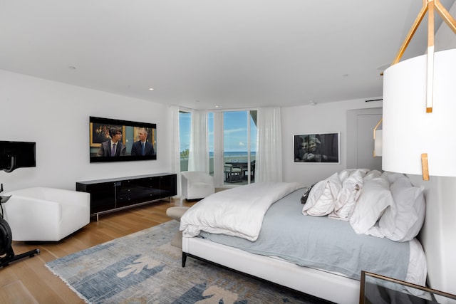 bedroom featuring access to exterior, wood-type flooring, and expansive windows