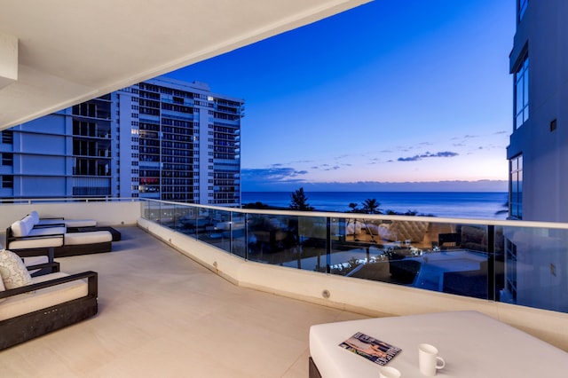 balcony at dusk featuring a water view