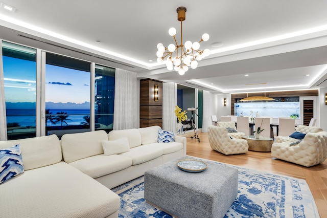 living room with a tray ceiling, a notable chandelier, and hardwood / wood-style flooring