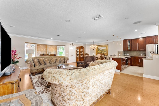 living room with a chandelier, a textured ceiling, light hardwood / wood-style floors, and crown molding