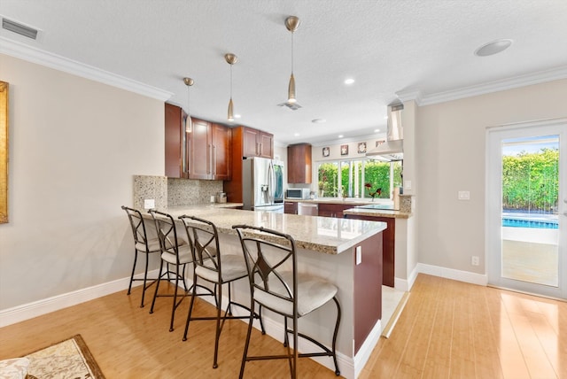 kitchen featuring hanging light fixtures, light hardwood / wood-style flooring, a textured ceiling, kitchen peninsula, and stainless steel appliances