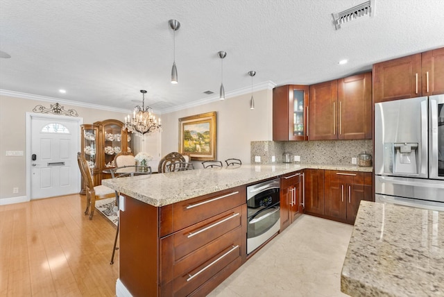 kitchen featuring a kitchen breakfast bar, stainless steel appliances, decorative light fixtures, light hardwood / wood-style flooring, and a notable chandelier