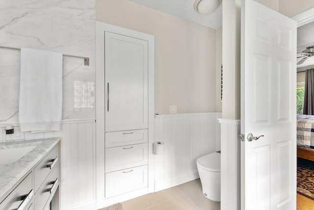 bathroom with tile patterned flooring, vanity, ceiling fan, and toilet