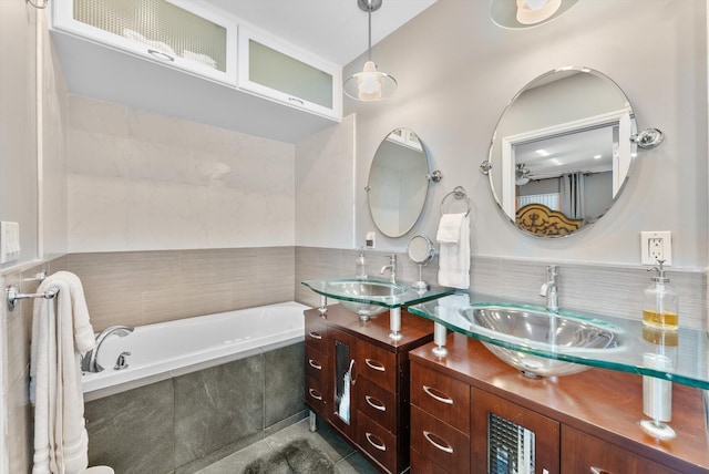 bathroom with tile patterned flooring, vanity, and a relaxing tiled tub