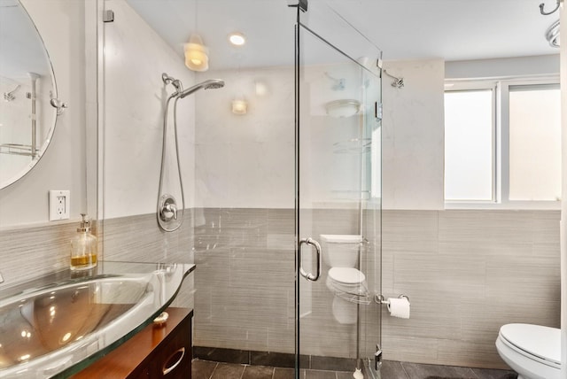 bathroom featuring an enclosed shower, vanity, toilet, and tile walls