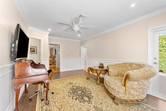 living area with ceiling fan, dark hardwood / wood-style floors, and ornamental molding