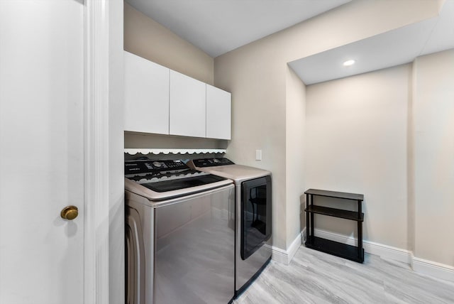 clothes washing area with cabinets, light wood-type flooring, and washing machine and dryer