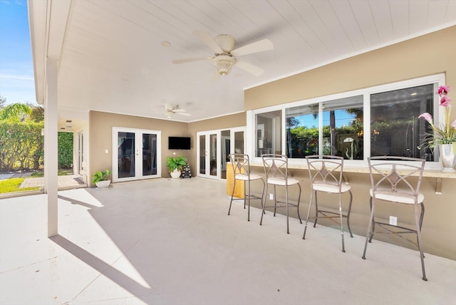 view of patio with ceiling fan, french doors, and a bar