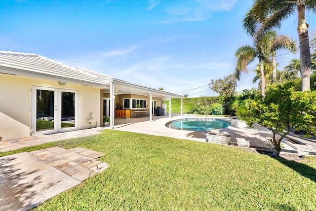 view of pool with french doors, a patio, and a yard