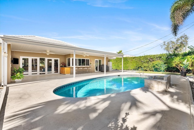 view of pool with ceiling fan, exterior bar, and a patio