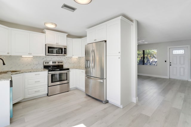 kitchen featuring light stone countertops, tasteful backsplash, stainless steel appliances, sink, and white cabinets