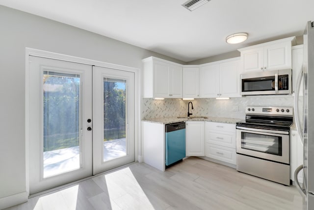 kitchen with appliances with stainless steel finishes, backsplash, french doors, sink, and white cabinetry