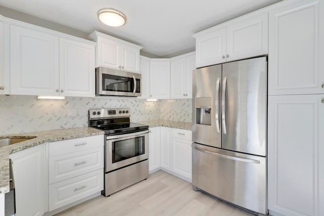 kitchen featuring white cabinets, decorative backsplash, light stone countertops, and appliances with stainless steel finishes