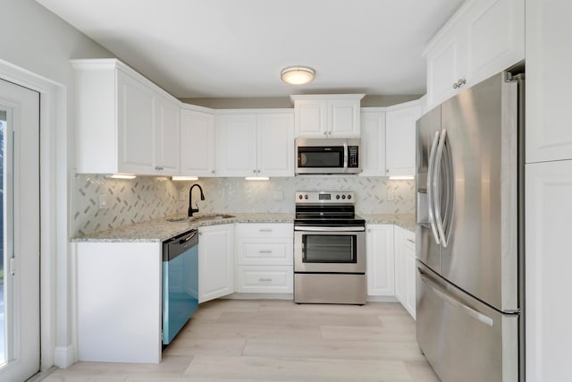 kitchen with white cabinetry, sink, light stone counters, backsplash, and appliances with stainless steel finishes