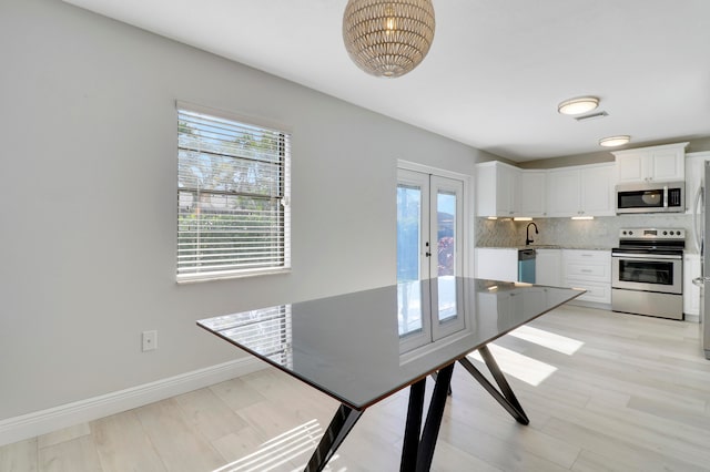 kitchen with appliances with stainless steel finishes, tasteful backsplash, light stone counters, sink, and white cabinetry