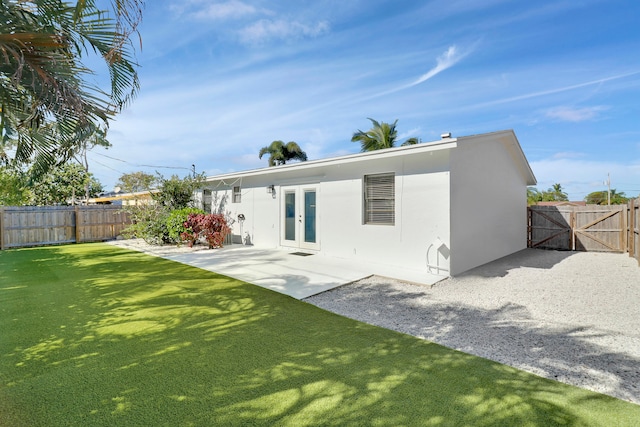 rear view of property featuring french doors, a yard, and a patio area