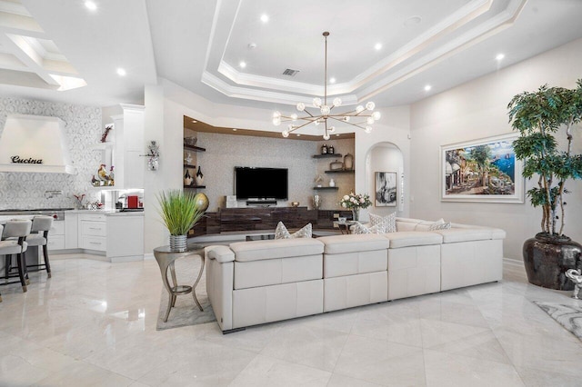 living room featuring a raised ceiling, crown molding, and a chandelier