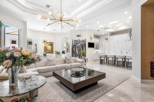 living room featuring coffered ceiling, sink, crown molding, a notable chandelier, and beam ceiling