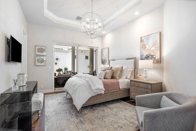 bedroom featuring a chandelier, hardwood / wood-style floors, and a raised ceiling