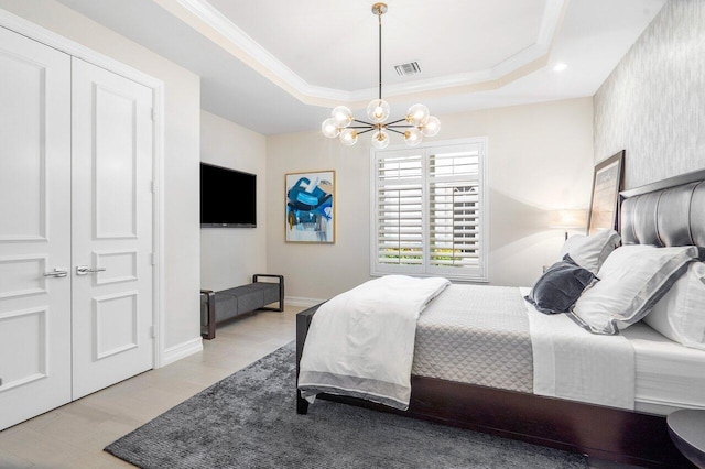 bedroom featuring a tray ceiling, a closet, and an inviting chandelier