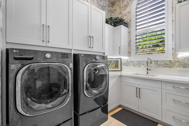 washroom featuring washer and dryer, cabinets, and sink