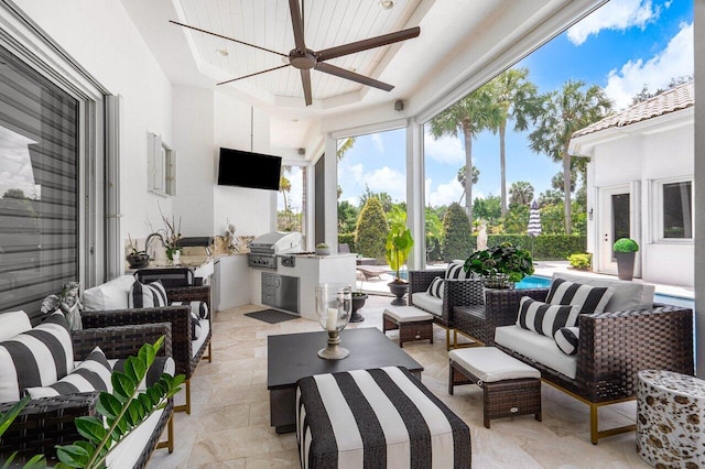 sunroom featuring a raised ceiling and ceiling fan