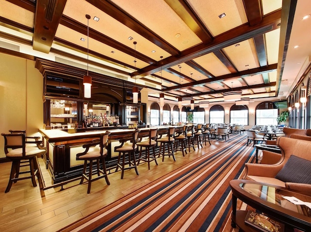 bar with beam ceiling, hanging light fixtures, coffered ceiling, and light wood-type flooring