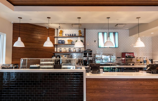 bar featuring tasteful backsplash, wood walls, and pendant lighting