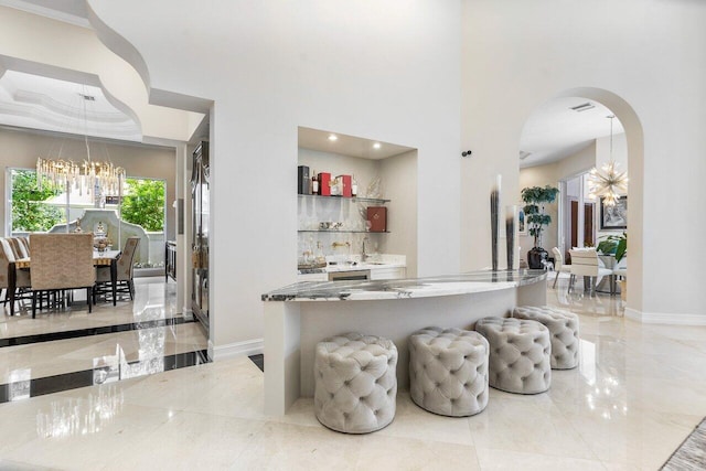 bar featuring crown molding, stone countertops, decorative light fixtures, and an inviting chandelier