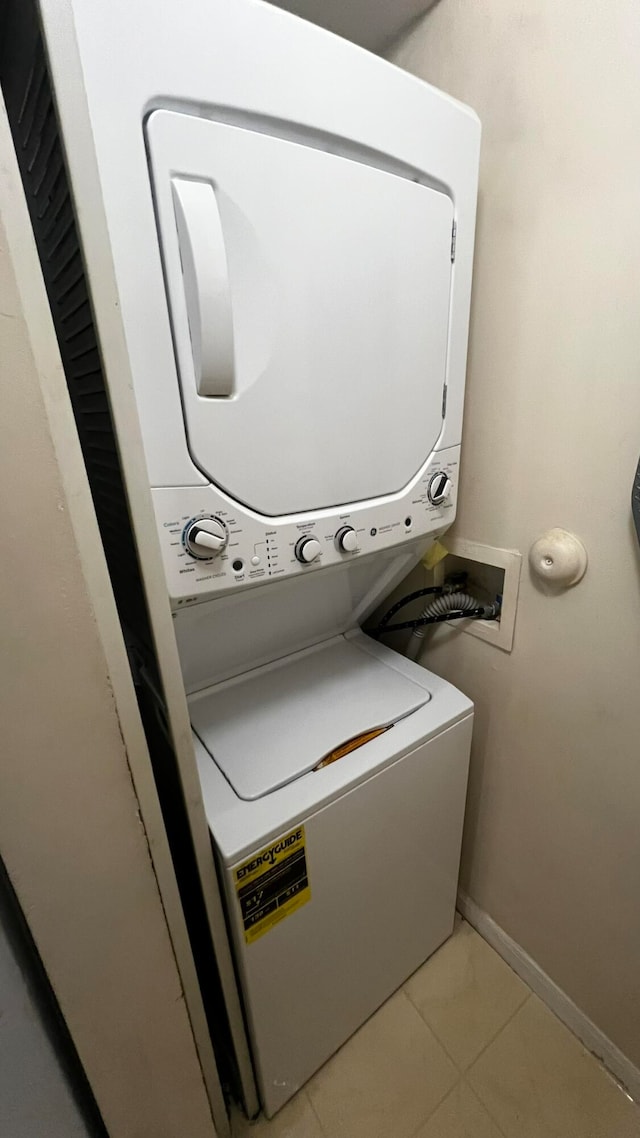 laundry room featuring stacked washer / drying machine and light tile patterned flooring