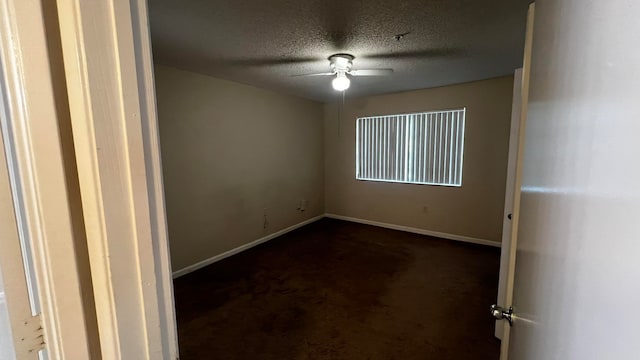 empty room featuring a textured ceiling, dark carpet, and ceiling fan