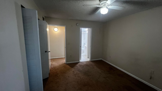 empty room featuring ceiling fan, dark carpet, and a textured ceiling