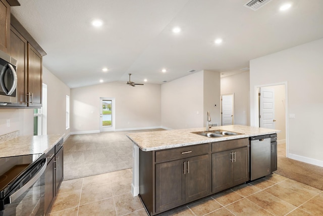 kitchen with stainless steel appliances, vaulted ceiling, light colored carpet, and a center island with sink