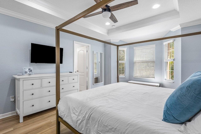 bedroom with ceiling fan, a tray ceiling, crown molding, and light hardwood / wood-style flooring