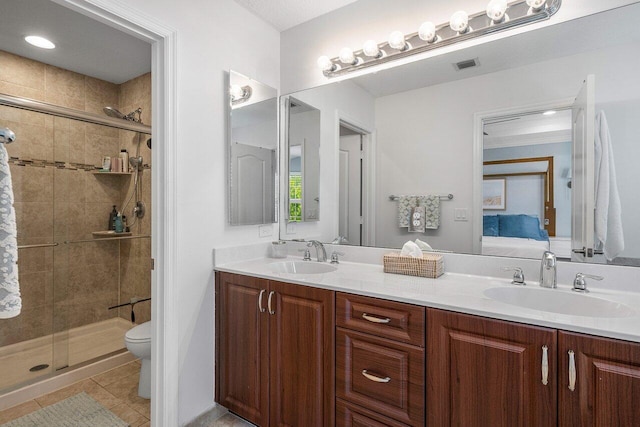 bathroom featuring toilet, vanity, tile patterned floors, and a shower with shower door