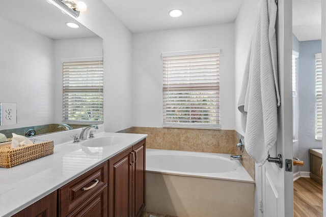 bathroom with a healthy amount of sunlight, a bathtub, hardwood / wood-style flooring, and vanity