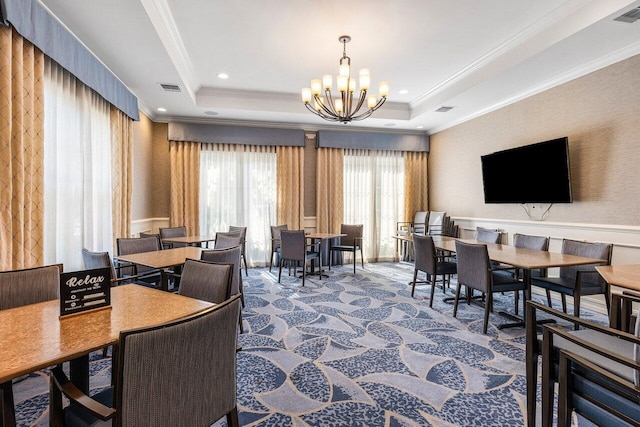 dining space with a tray ceiling, crown molding, and a chandelier