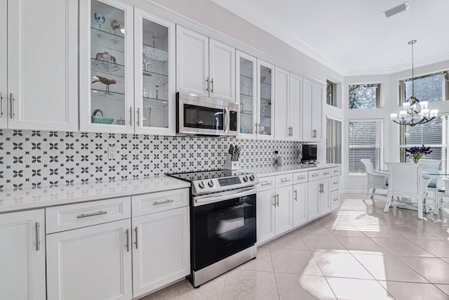 kitchen with backsplash, white cabinets, crown molding, appliances with stainless steel finishes, and light tile patterned flooring