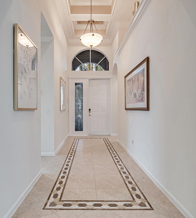 foyer entrance featuring light tile patterned floors, a towering ceiling, and ornamental molding