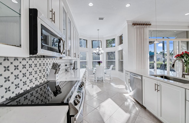 kitchen with a wealth of natural light, white cabinetry, pendant lighting, and stainless steel appliances