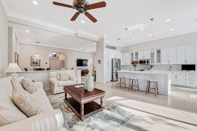 living room with ceiling fan with notable chandelier, light tile patterned floors, and ornamental molding